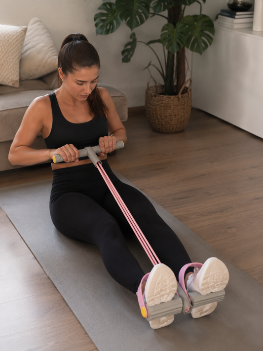 Vrouw traint thuis met weerstandsband set op yogamat – roeioefening voor buik- en rugspieren